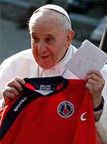 Pope Francis holds up a jersey and notes that were presented to him during a March 2015 visit to a parish outside Rome. CNS Photo/Paul Haring
