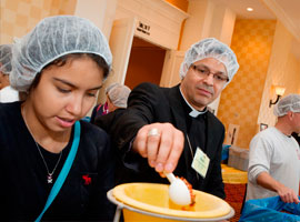 A parish volunteer and Bishop Rojas help with a service project prior to November 2012 USCCB meeting.