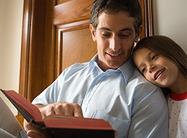 A father reads to his young daughter.