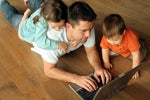 Young father surfs the net with his two toddlers. 