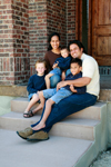 Young family sits on the steps together. 