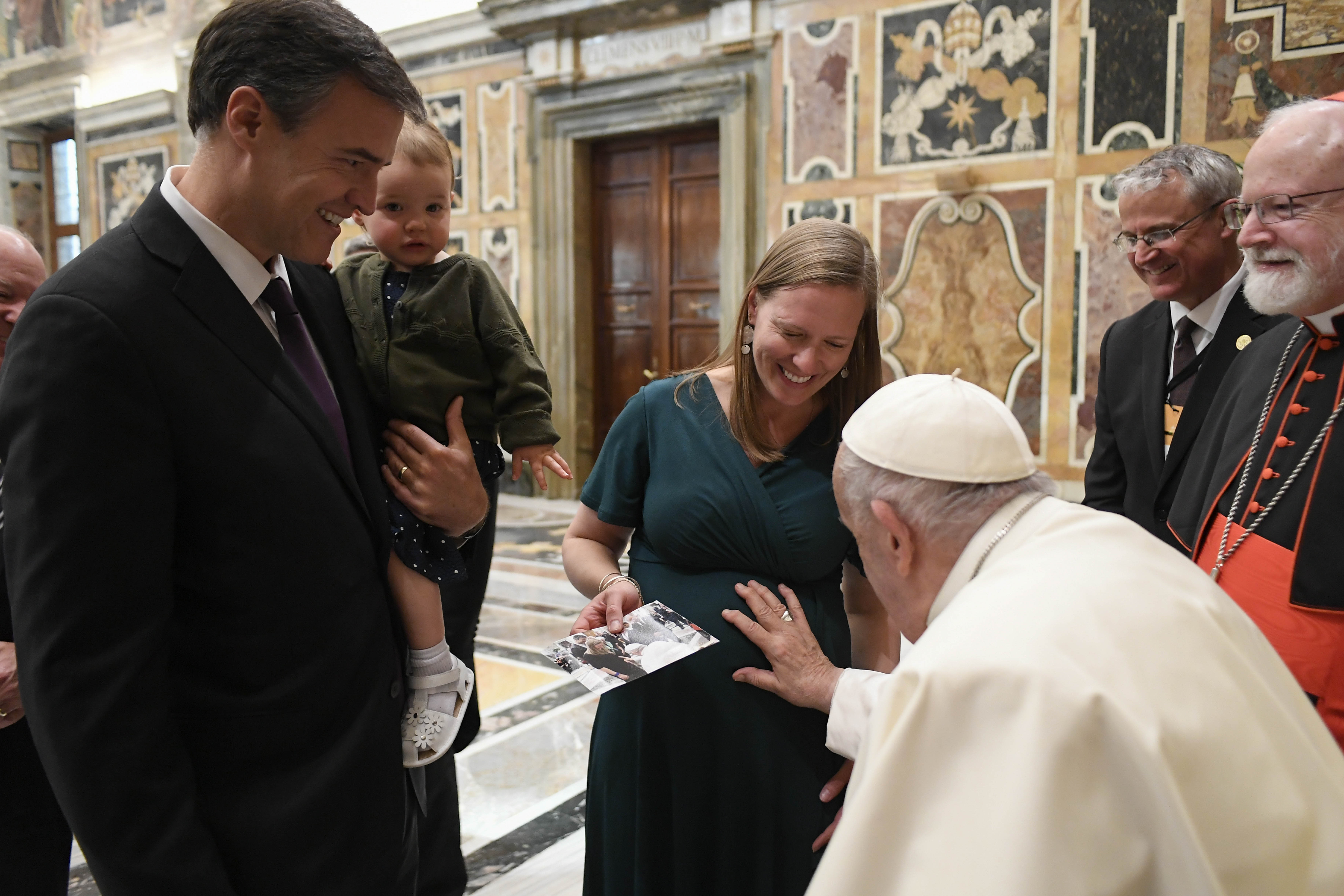 Pope Francis blesses a pregnant woman's child.