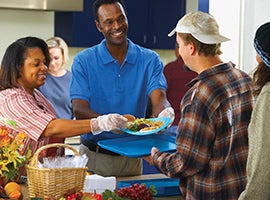 Volunteers serving a meal to a needy person.