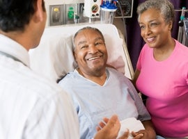 Man in hospital bed with wife by his side