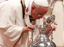 Pope Francis breathes over chrism oil, a gesture symbolizing the infusion of the Holy Spirit, during Holy Thursday chrism Mass in St. Peter's Basilica in 2014. CNS photo/Paul Haring