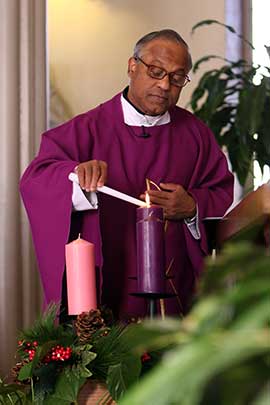 Father Francis Lasrado lights a candle in an Advent wreath at Infant Jesus Church in Port Jefferson, N.Y., on the first day of Advent in 2015. CNS photo/Gregory A. Shemitz