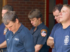 Firefighters from Engine Co. 205 and Ladder Co. 118 listen as names of their fallen comrades are read in at a New York memorial service marking the first anniversary of the 9/11 attacks. CNS Photo/Bob Roller.