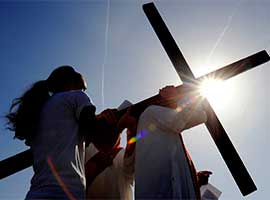 Clergy and parishioners assist one anotheras a large cross is transferred from one person to another during the Stations of the Cross in Reparation for Abortion, an annual Good Friday procession in Rochester, N.Y. CNS photo/Mike Crupi, Catholic Courier