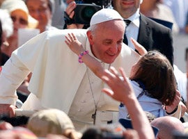 Pope Francis accepts a hug from a girl as he arrives to celebrate Mass in St. Peter's Square at the Vatican. (CNS photo/Paul Haring)