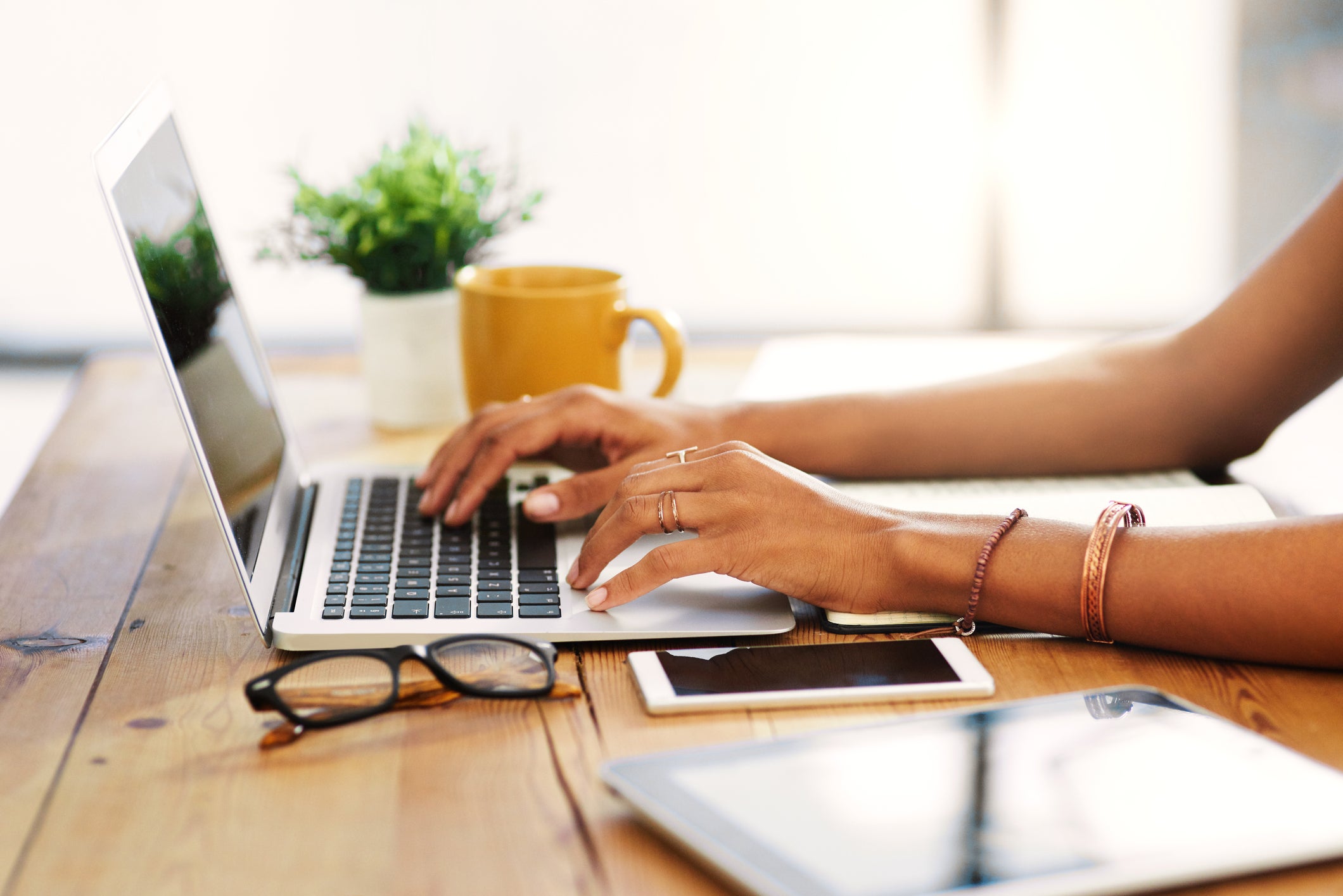 Woman typing on a laptop with coffee and notepad