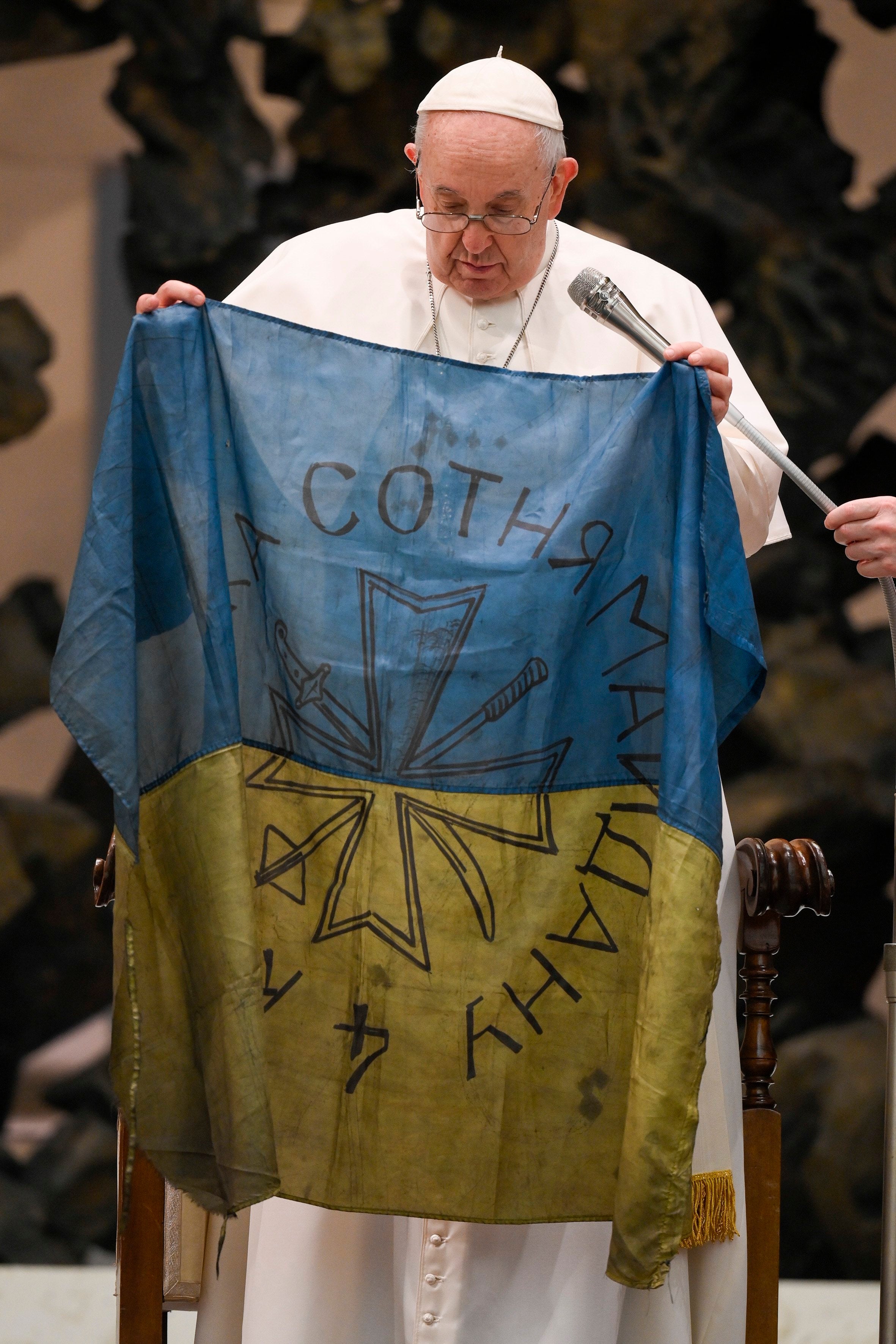 Pope Francis holds up a Ukrainian flag.