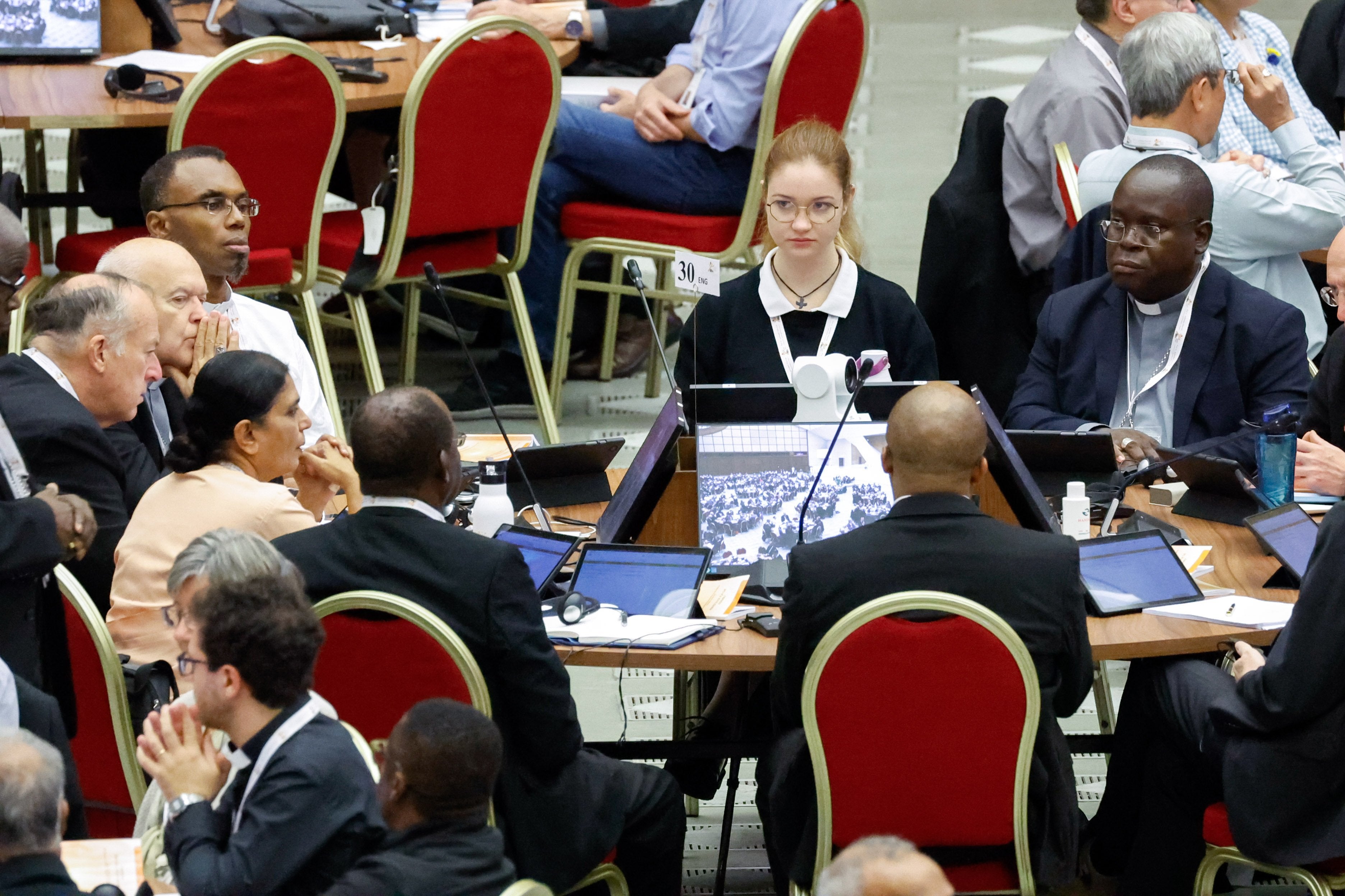 Members of the assembly of the Synod of Bishops pray before a working session.