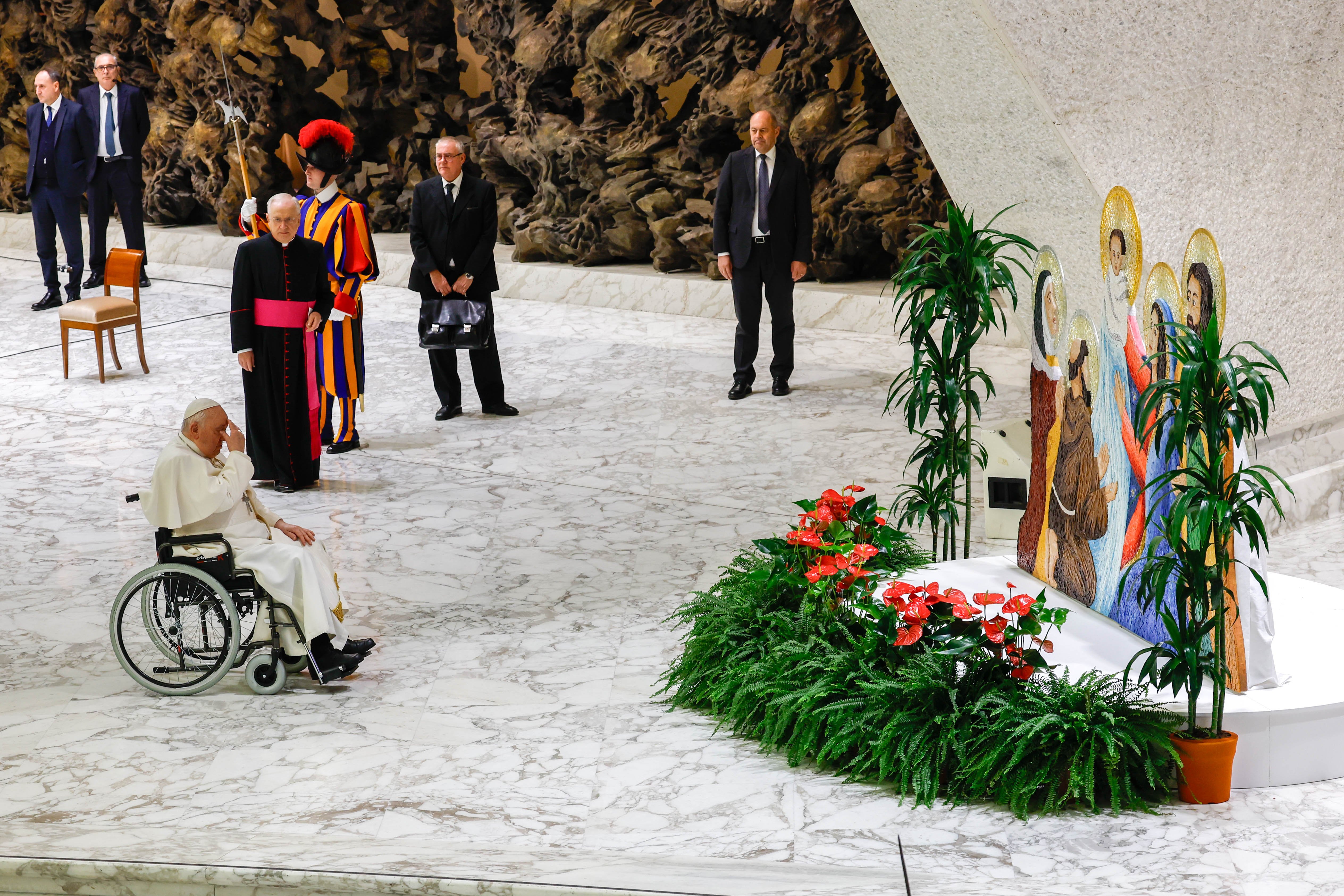 Pope Francis prays in front of a Nativity scene.