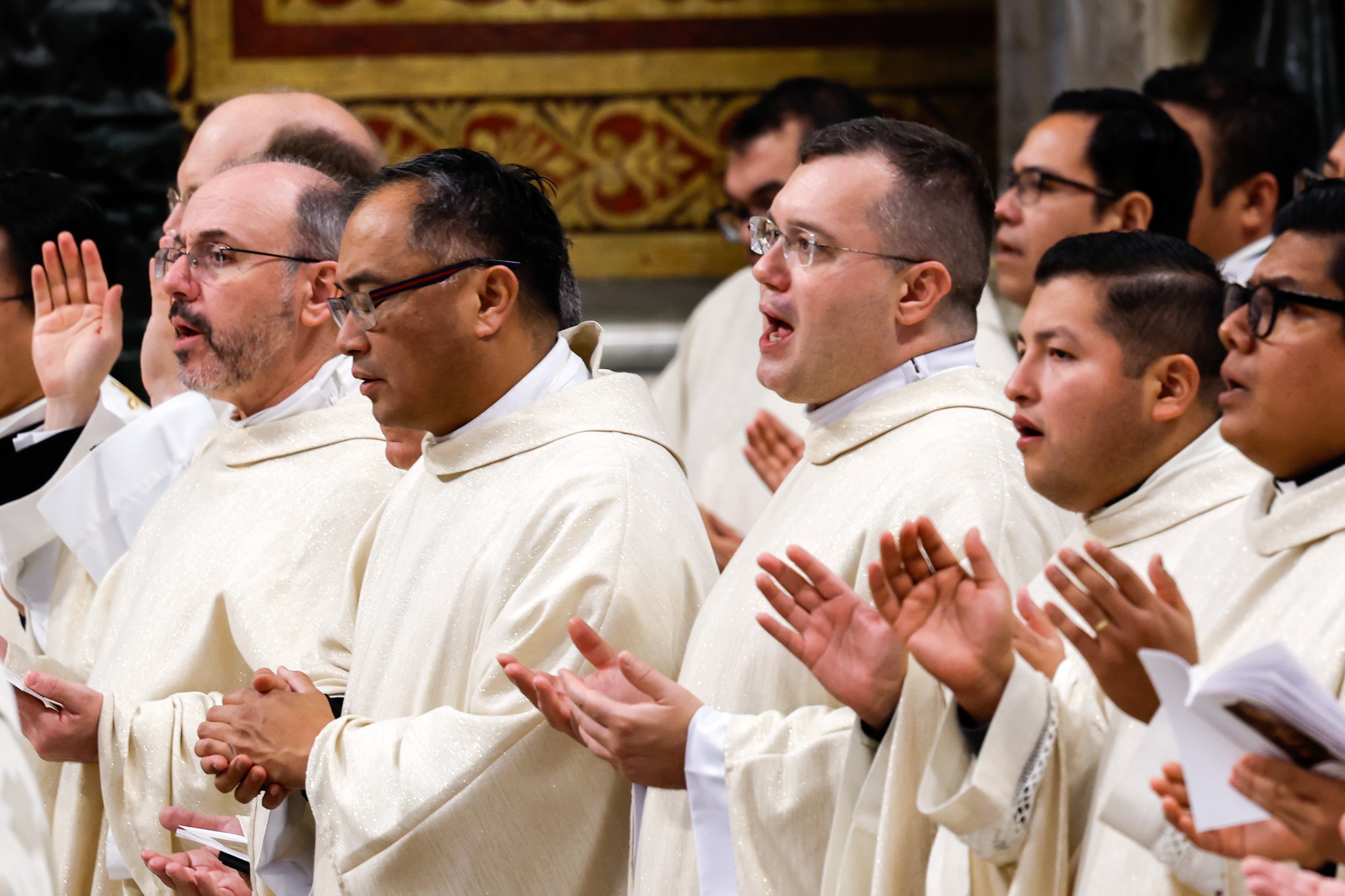 Priests pray during Pope Francis' Mass.