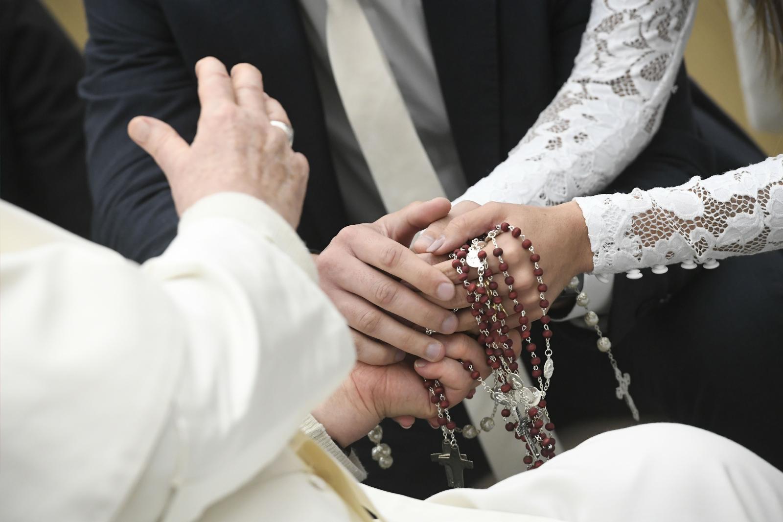 Pope Francis shakes hands with a bride.