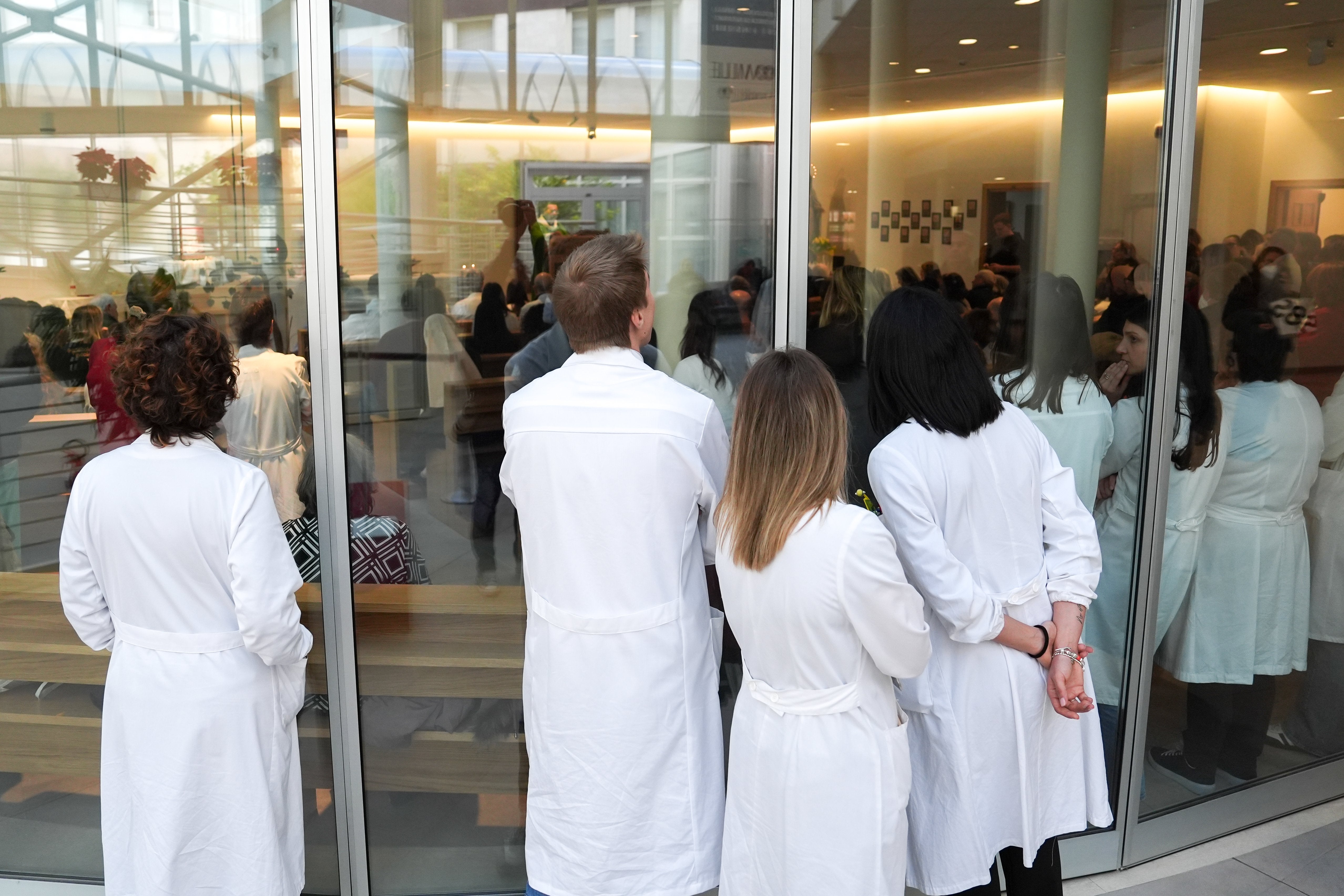 Doctors and nurses stand outside full chapel during Mass
