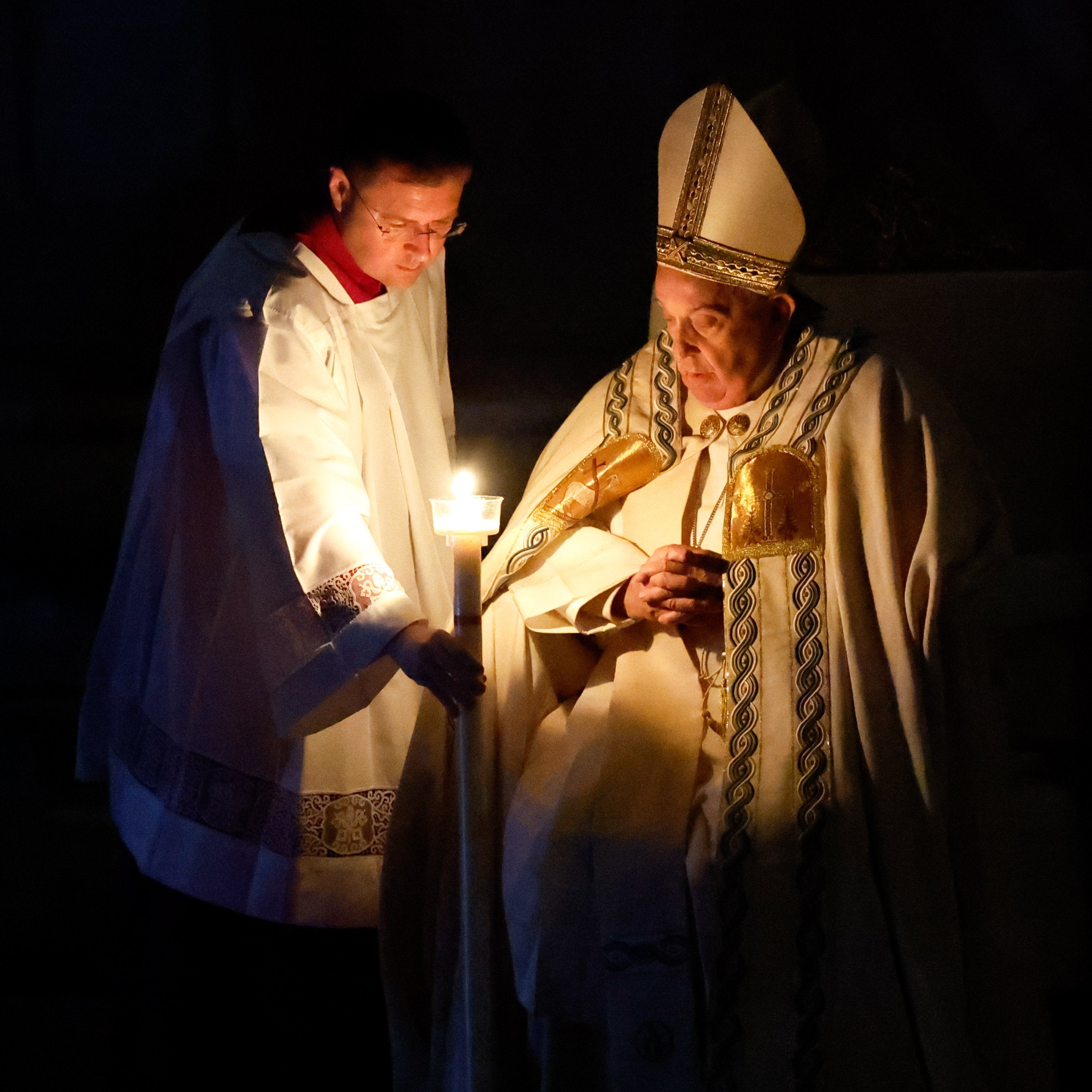 Pope Francis lights a candle at the Easter vigil Mass