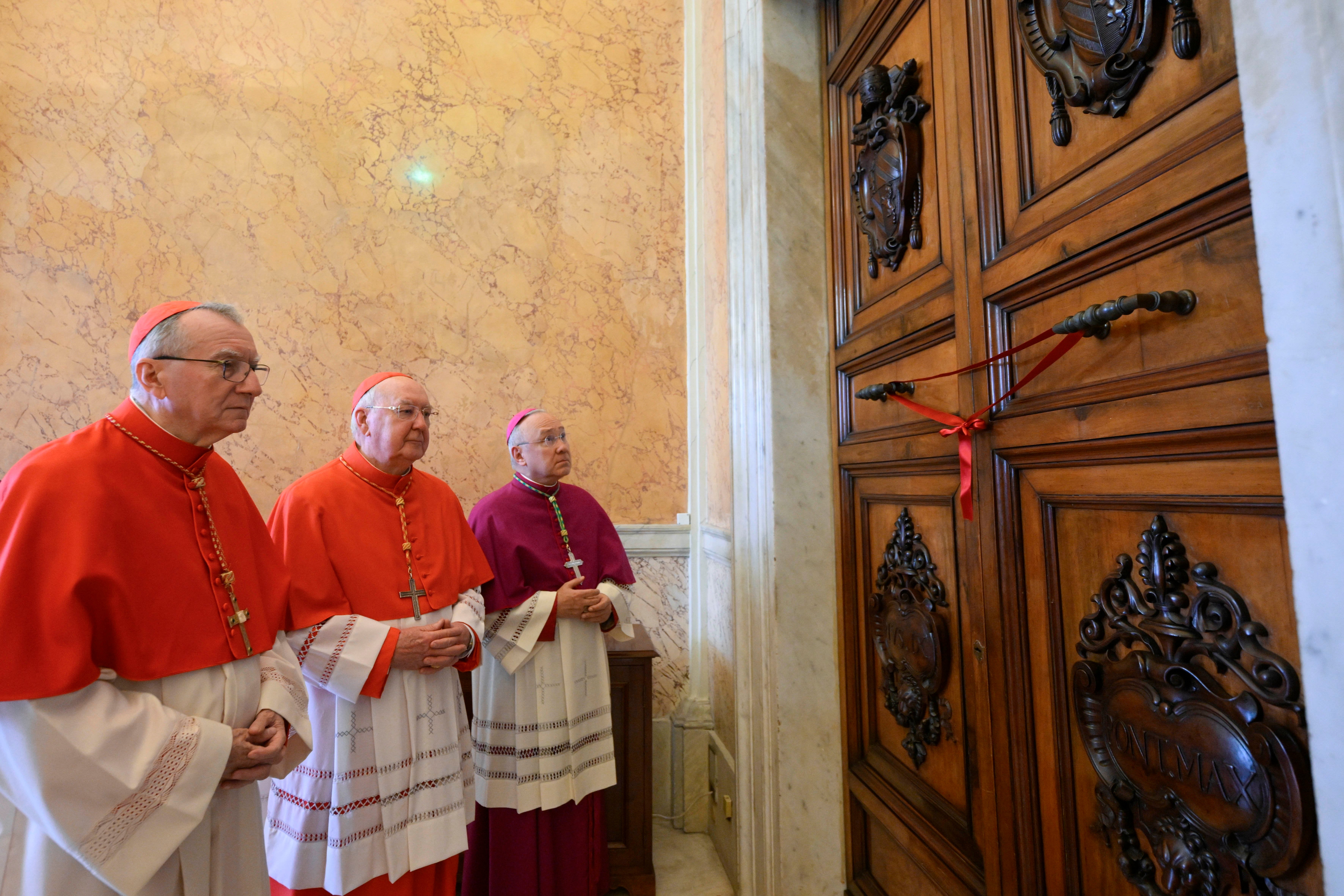 Cardinal Pietro Parolin, right, helps seal the papal apartments