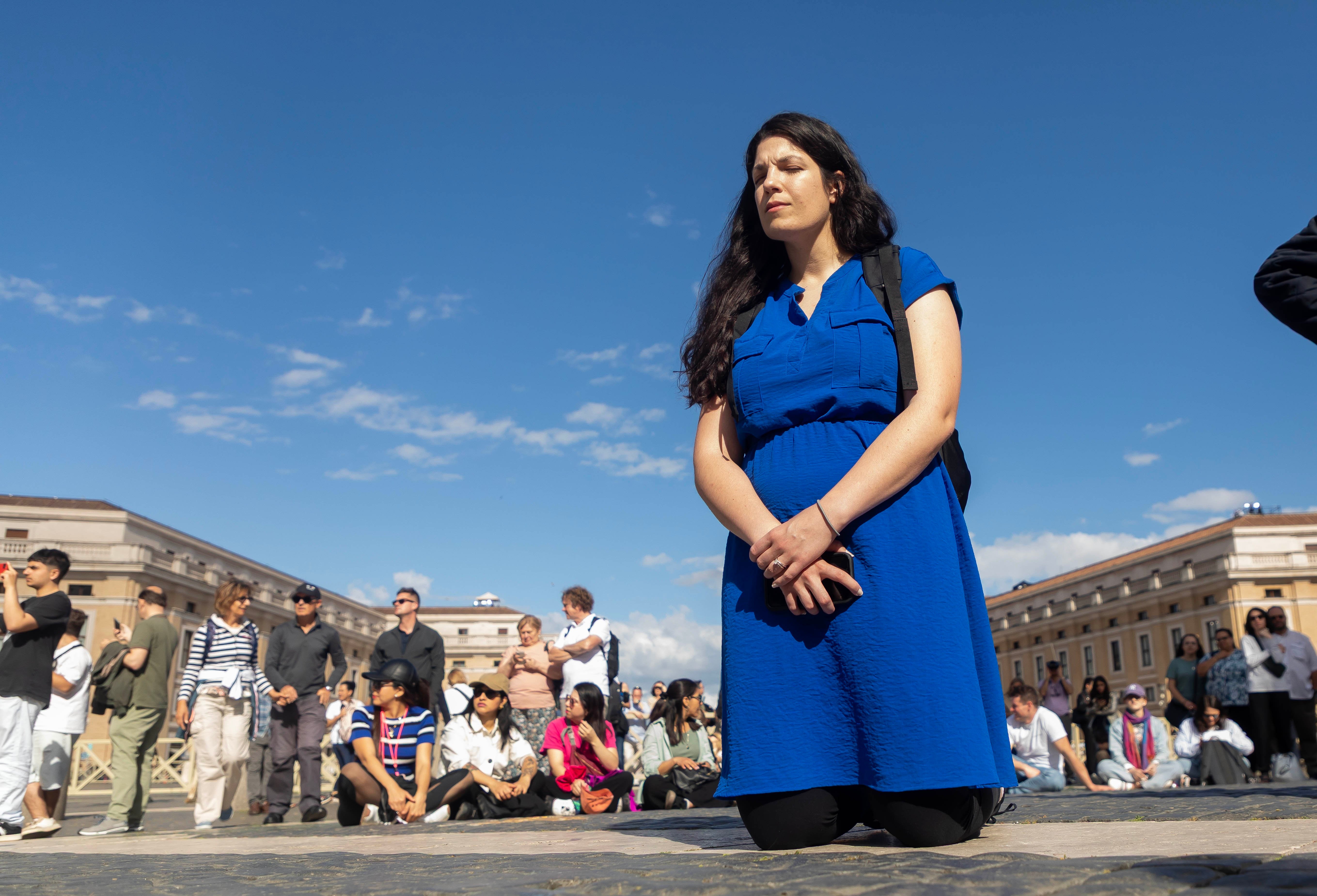 Woman prays in St. Peter's Square as the conclave begins