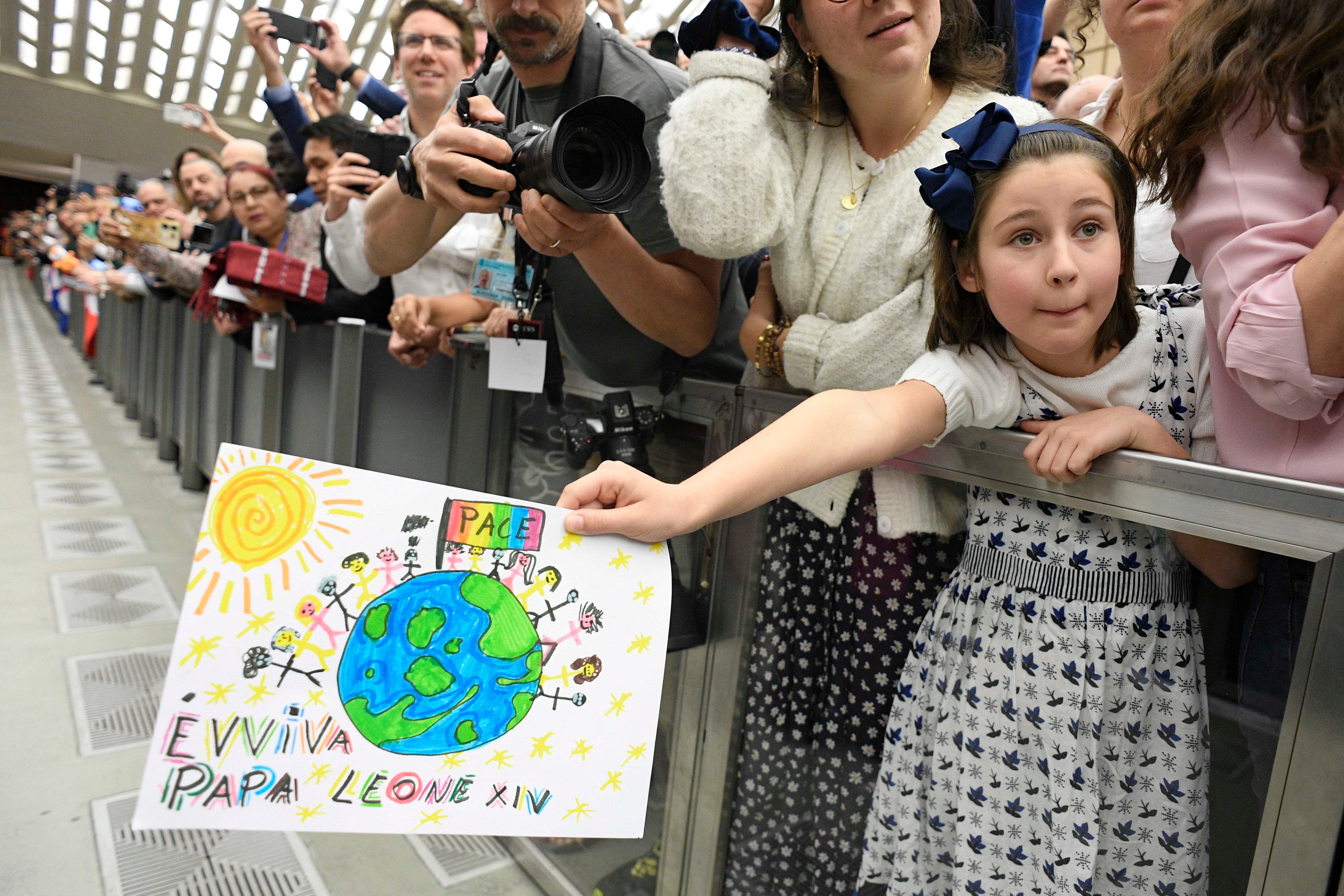 Little girls holds out a drawing for Pope Leo XIV