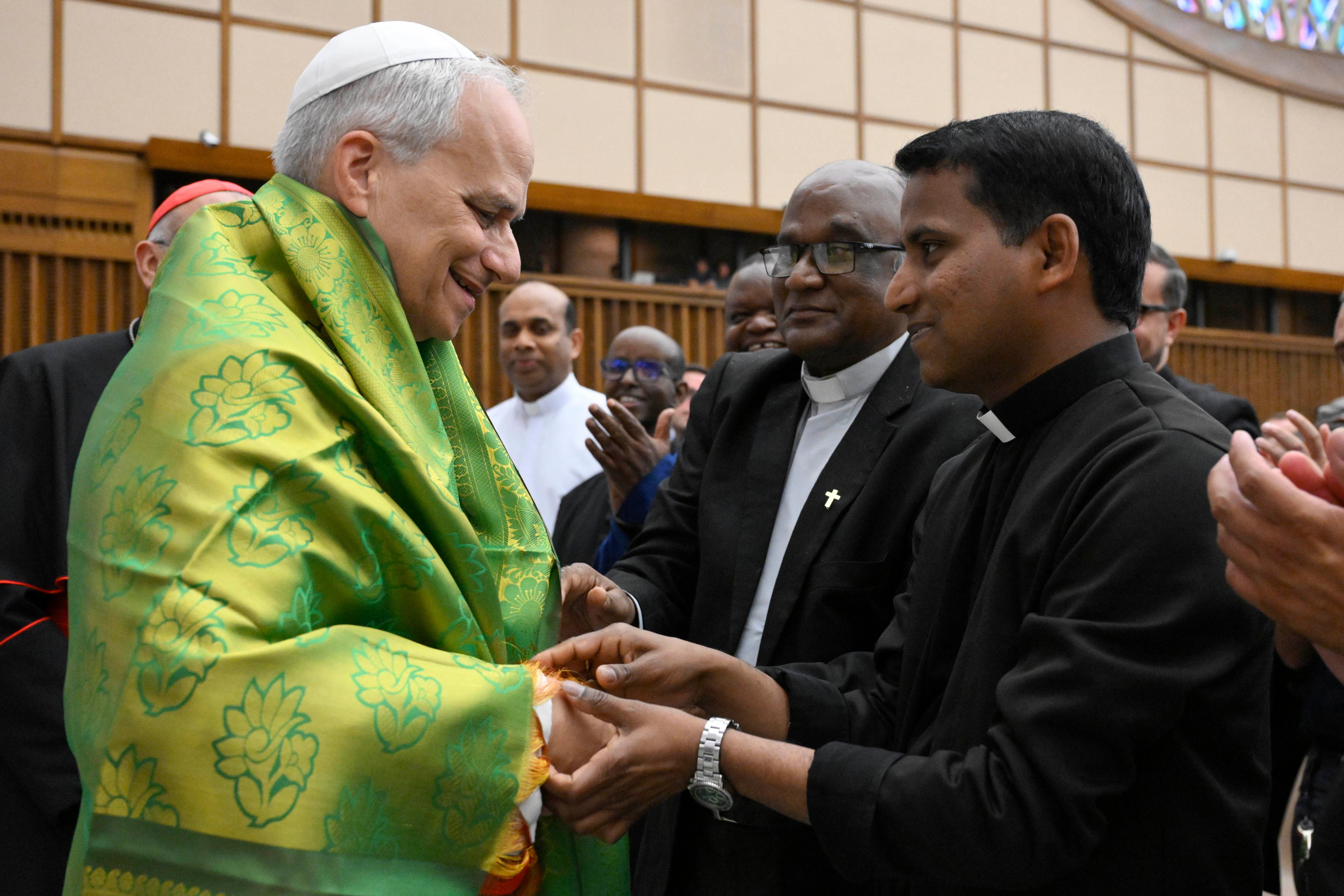 Pope Leo XIV receives a decorative shawl from a priest.