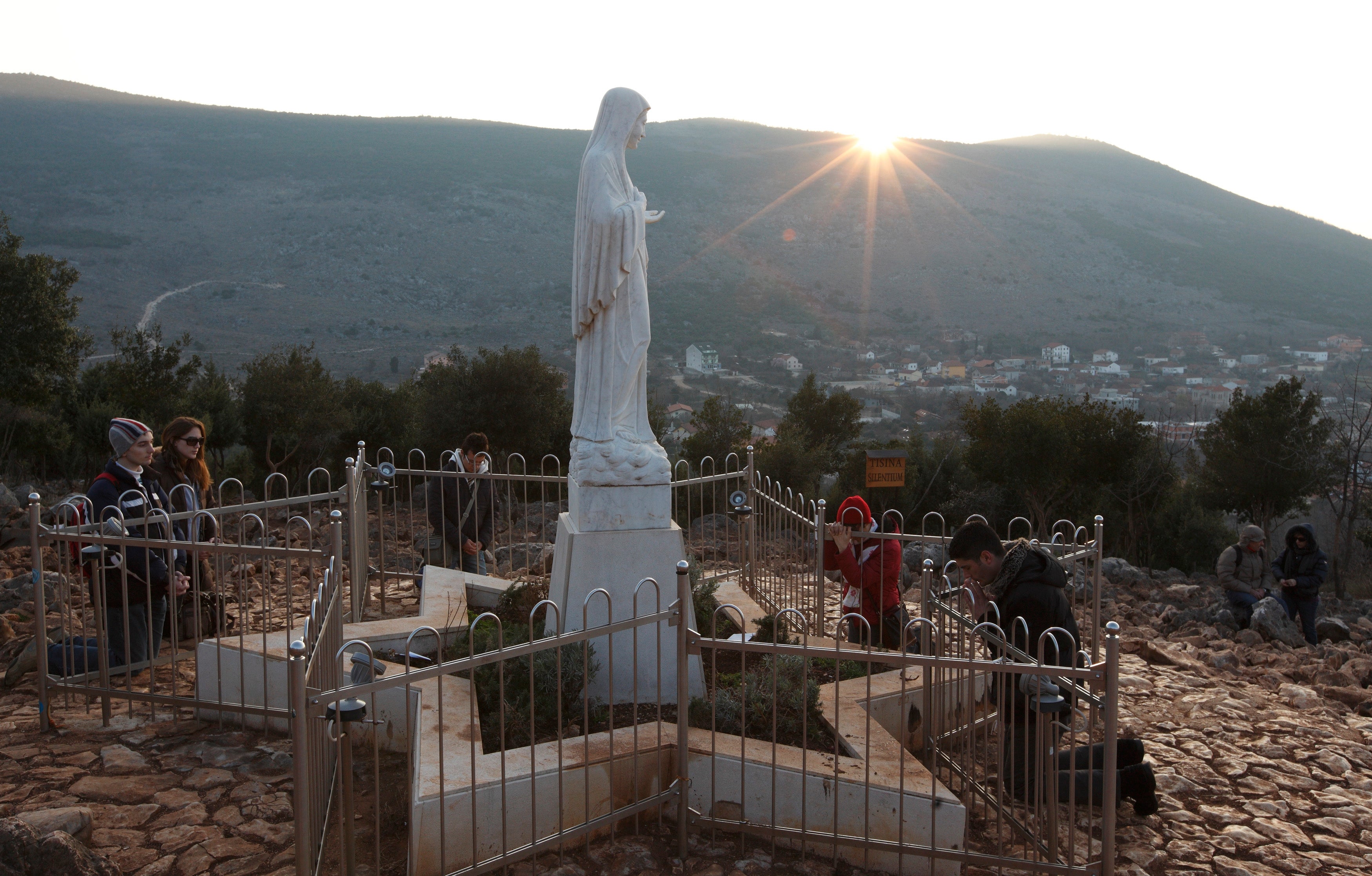 Pilgrims pray by statue of Mary in Medjugorje