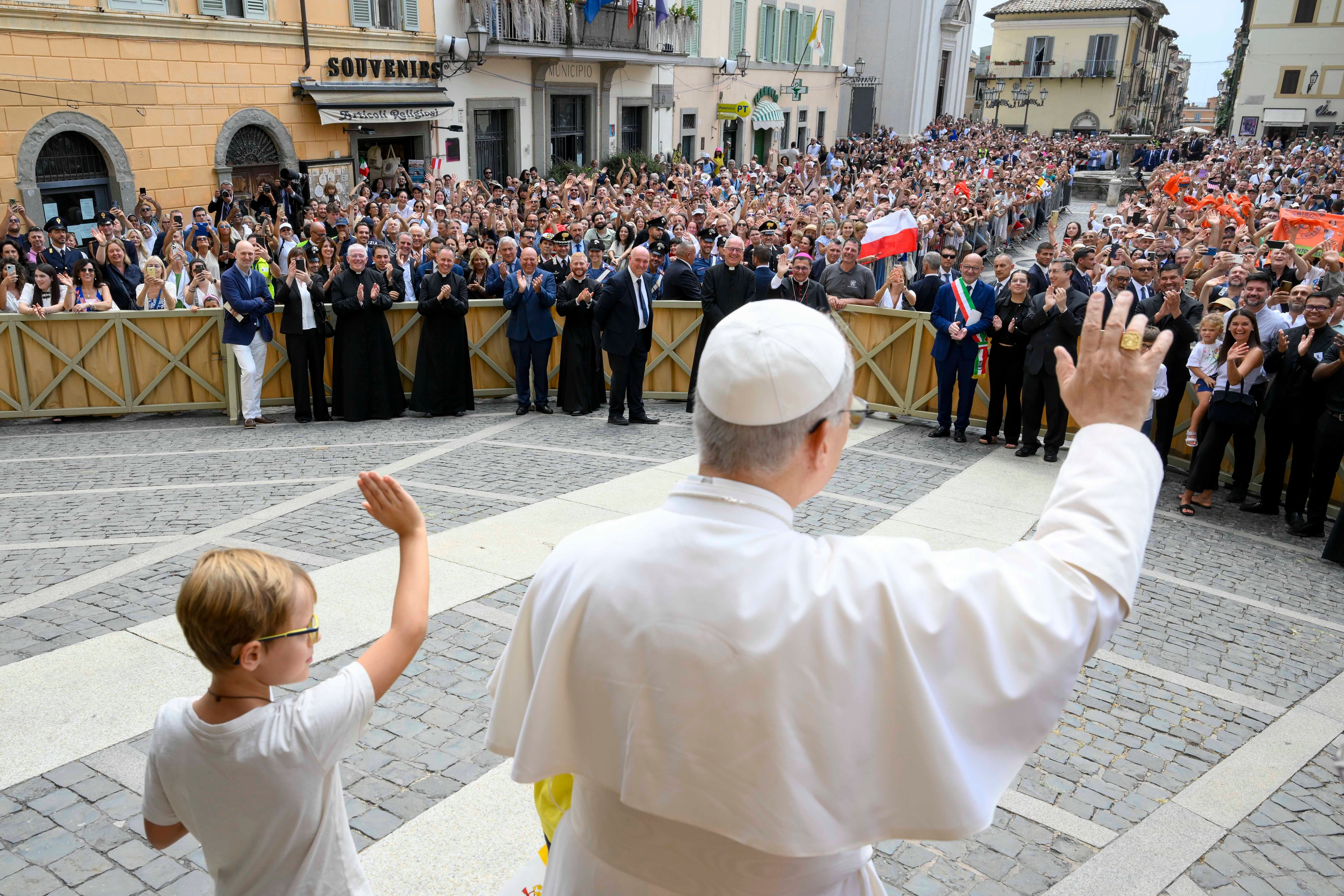 Pope Leo XIV and a boy wave to the crowd in Castel Gandolfo