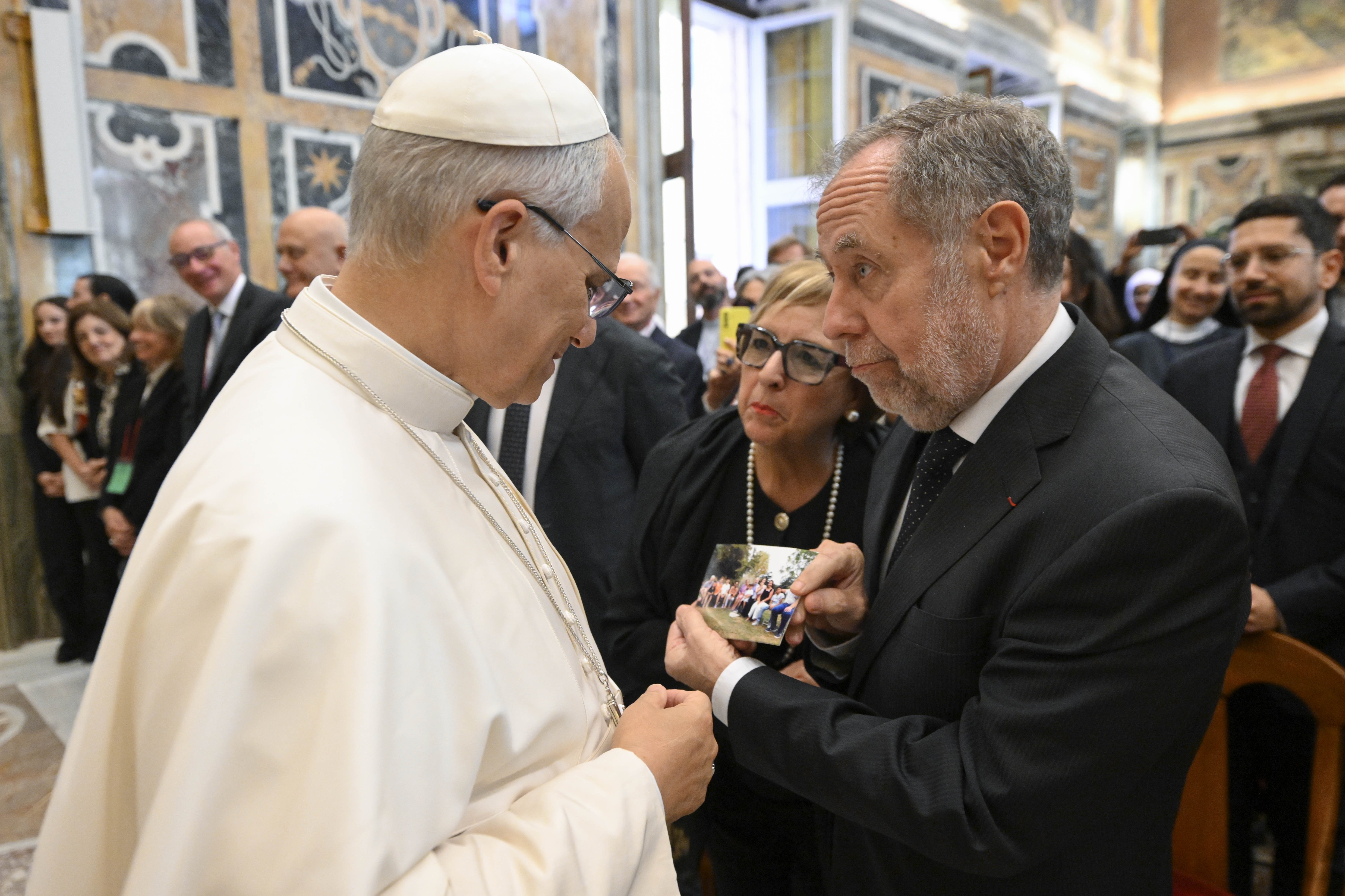 Pope Leo looks at a couple's photo