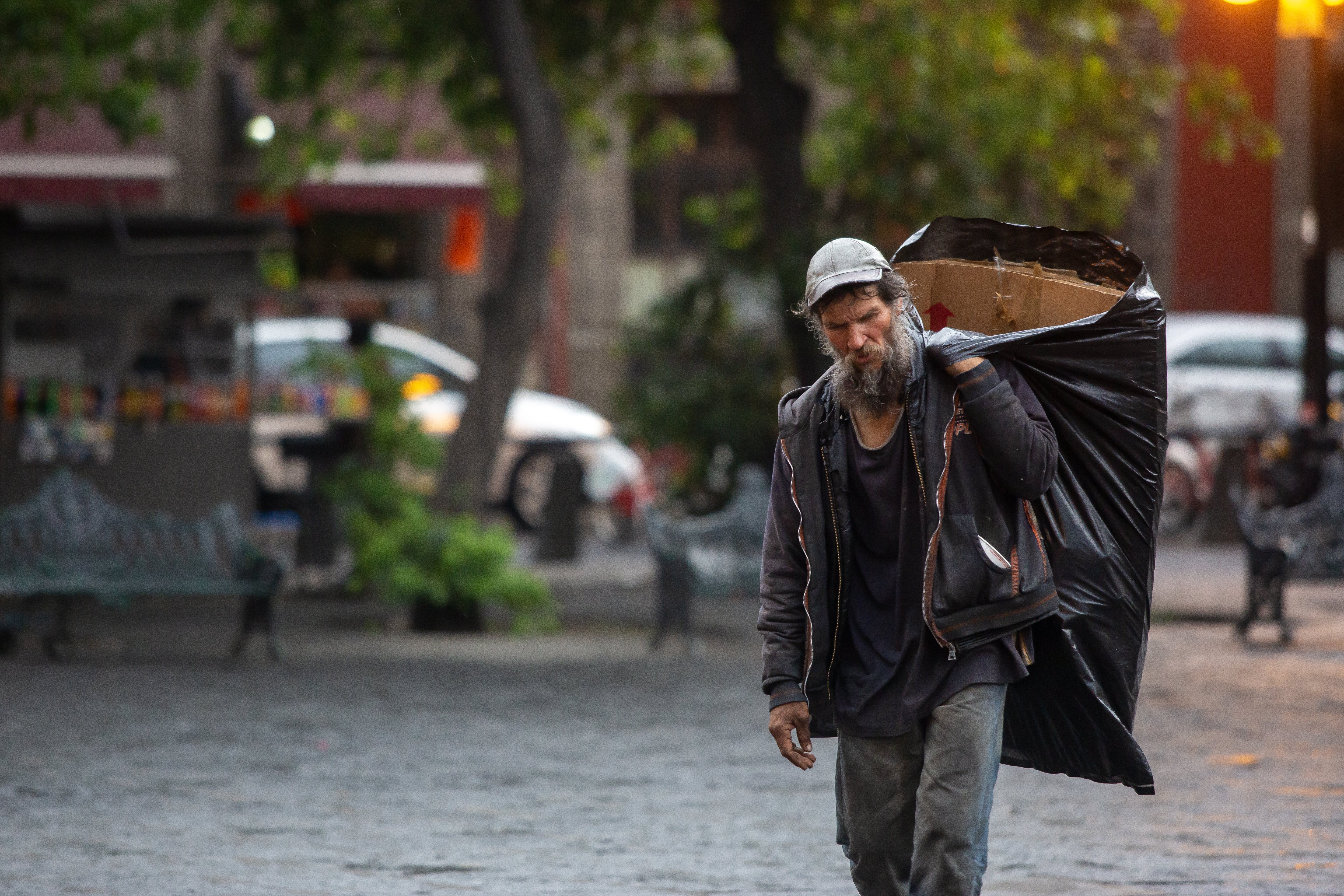 A man carries cardboard to sleep on