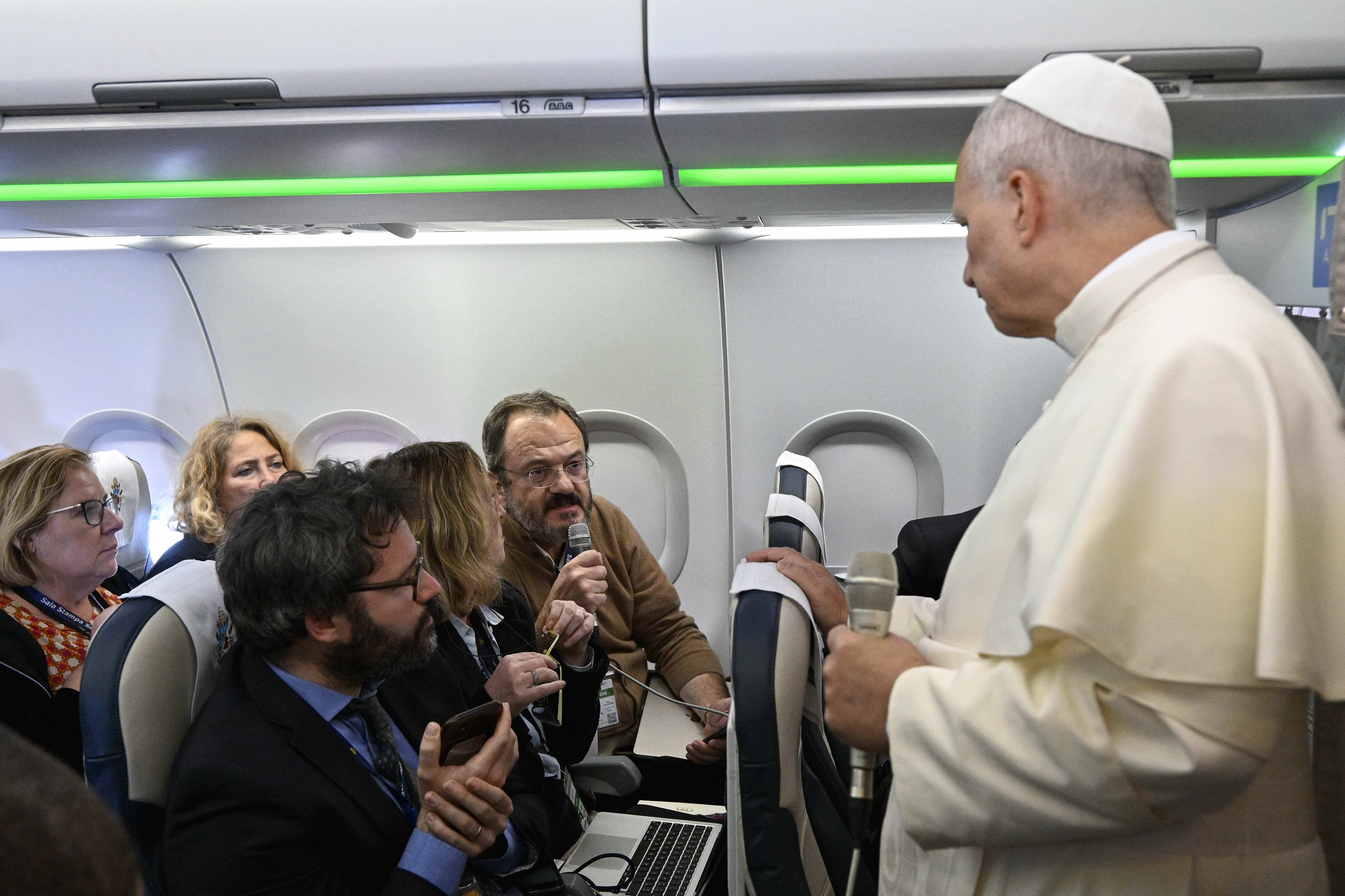 Pope Leo listens to a reporter's question on his plane