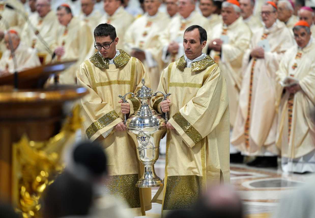 Deacons carry the blessed oils at the chrism Mass