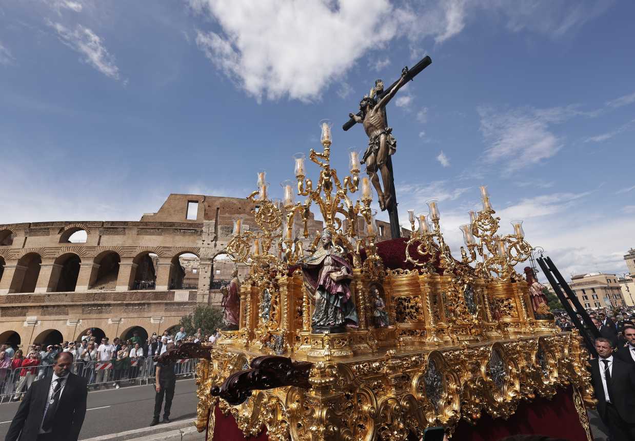A statue of the crucified Christ is carried past the Colosseum