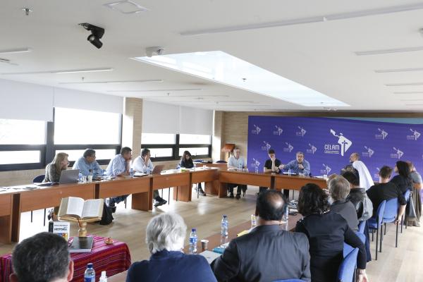 Participants at tables speak during a conference.