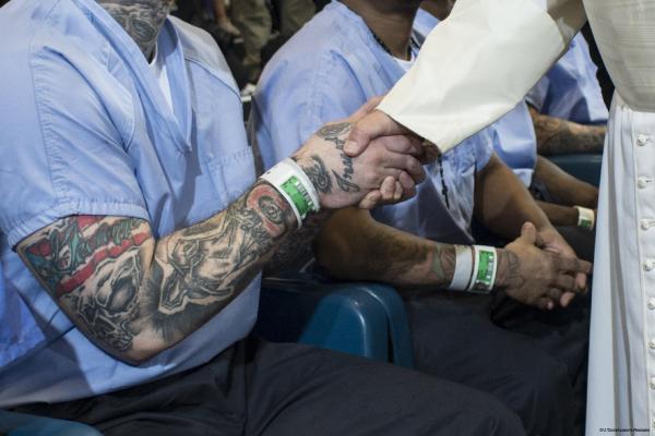 Pope Francis shakes hands with an incarcerated person.