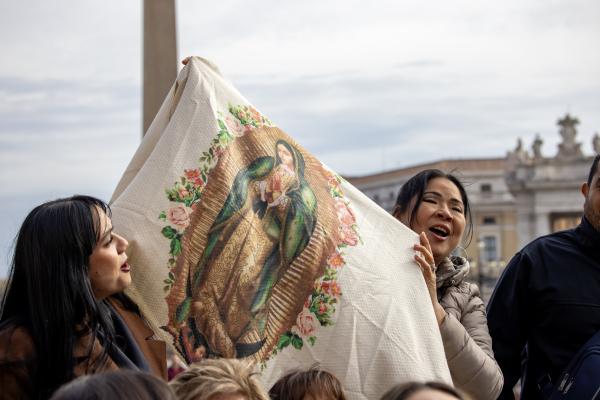 Women hold up an image of Our Lady of Guadalupe