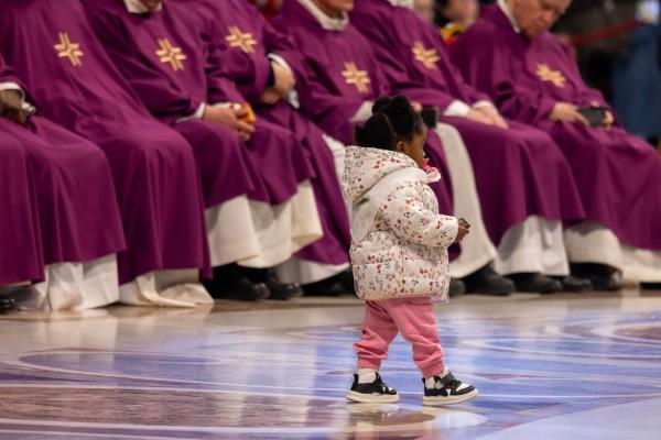 A little girl walks in front of clergy at Mass