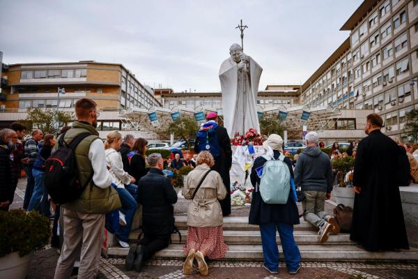 A group of Russian pilgrims prays during a rosary led by Archbishop Paolo Pezzi of Moscow, near a statue of St. John Paul II outside Rome's Gemelli Hospital.