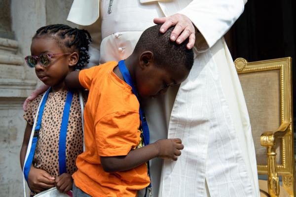 Migrant children grip Pope Francis' cassock