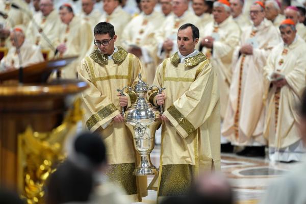 Deacons carry the blessed oils at the chrism Mass