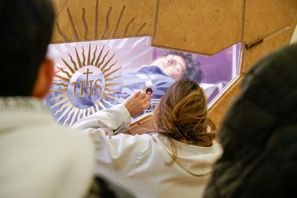 A woman prays before the tomb of Blessed Carlo Acutis.