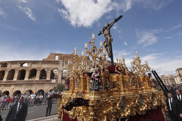 A statue of the crucified Christ is carried past the Colosseum