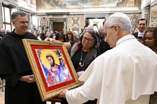 Pope Leo XIV receives a painting at a migration conference