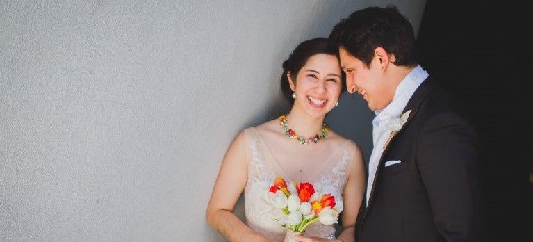 Hispanic Bride with bouquet looking at camera and Groom looking at Bride