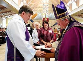 Bishop Ricken, Diocese of Green Bay, WI, signs the Book of the Elect during the Rite of Election