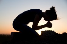 A young women kneels in prayer