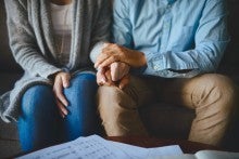 Man holds woman's hand to comfort her