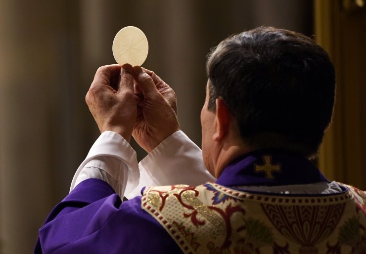 Priest holding up a communion during the consecration at Mass