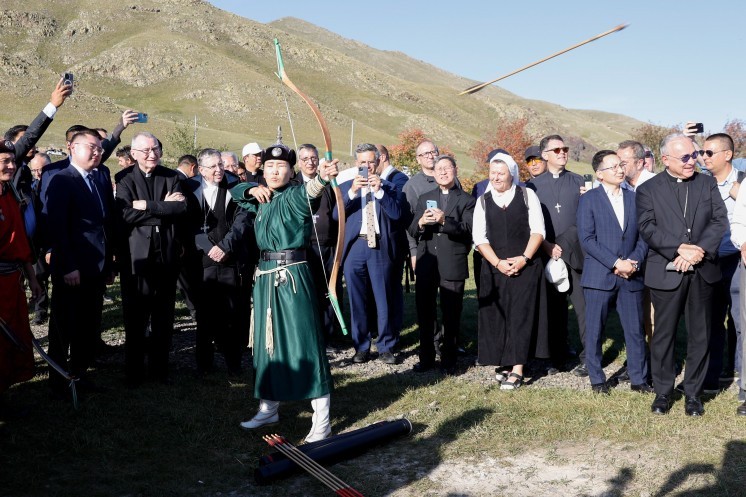Members of Pope Francis' entourage watch as a Mongolian archer performs at a cultural exhibition.