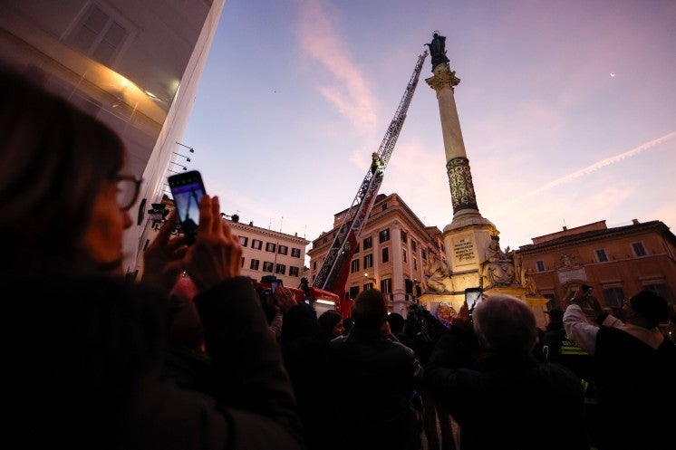 People take pictures of a Marian statue.