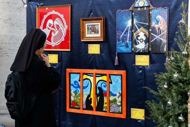 A religious sister looks at images of Nativity scenes.